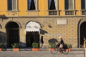 Woman riding a bicycle past a building in Florence, Italy during the winter.