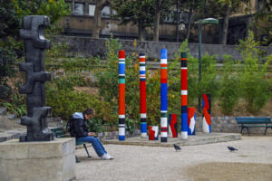 Woman sits near outdoor sculptures near the Seine in Paris, France