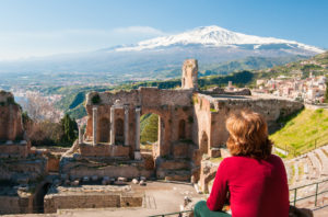 Woman sitting overlooking Roman ruins in Taormina, Sicily.